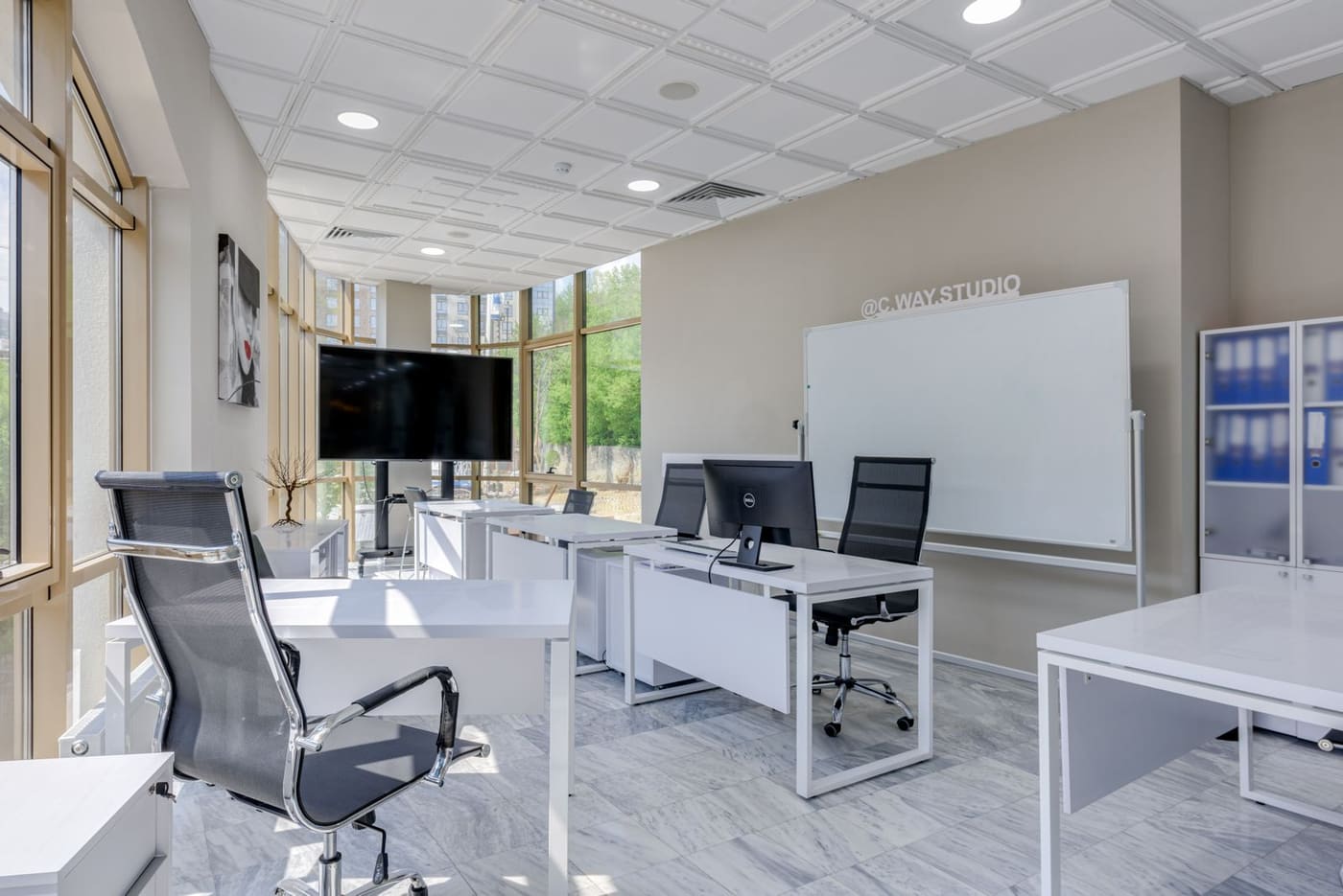 A clean office fit-out with desks, chairs and a display screen