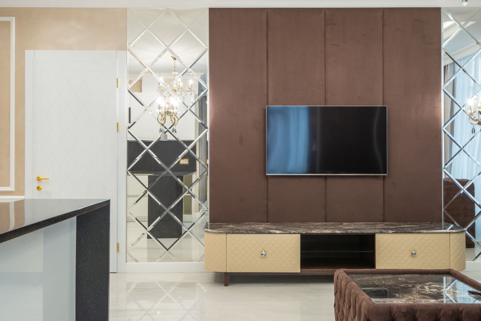 A warm living room with a panelled television wall, mirrored feature and marble flooring