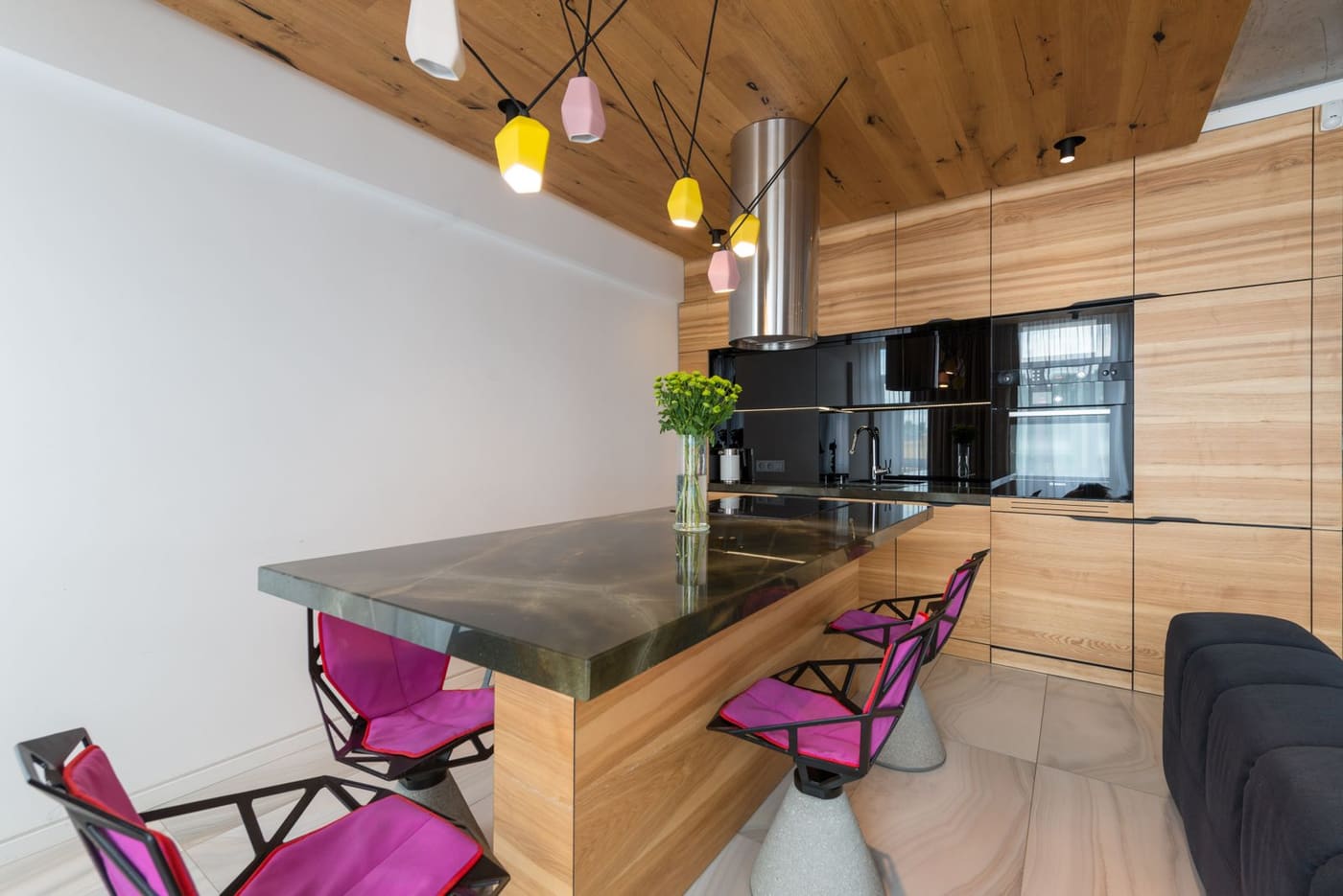 A modern timber kitchen with a stone island and pendant lamps
