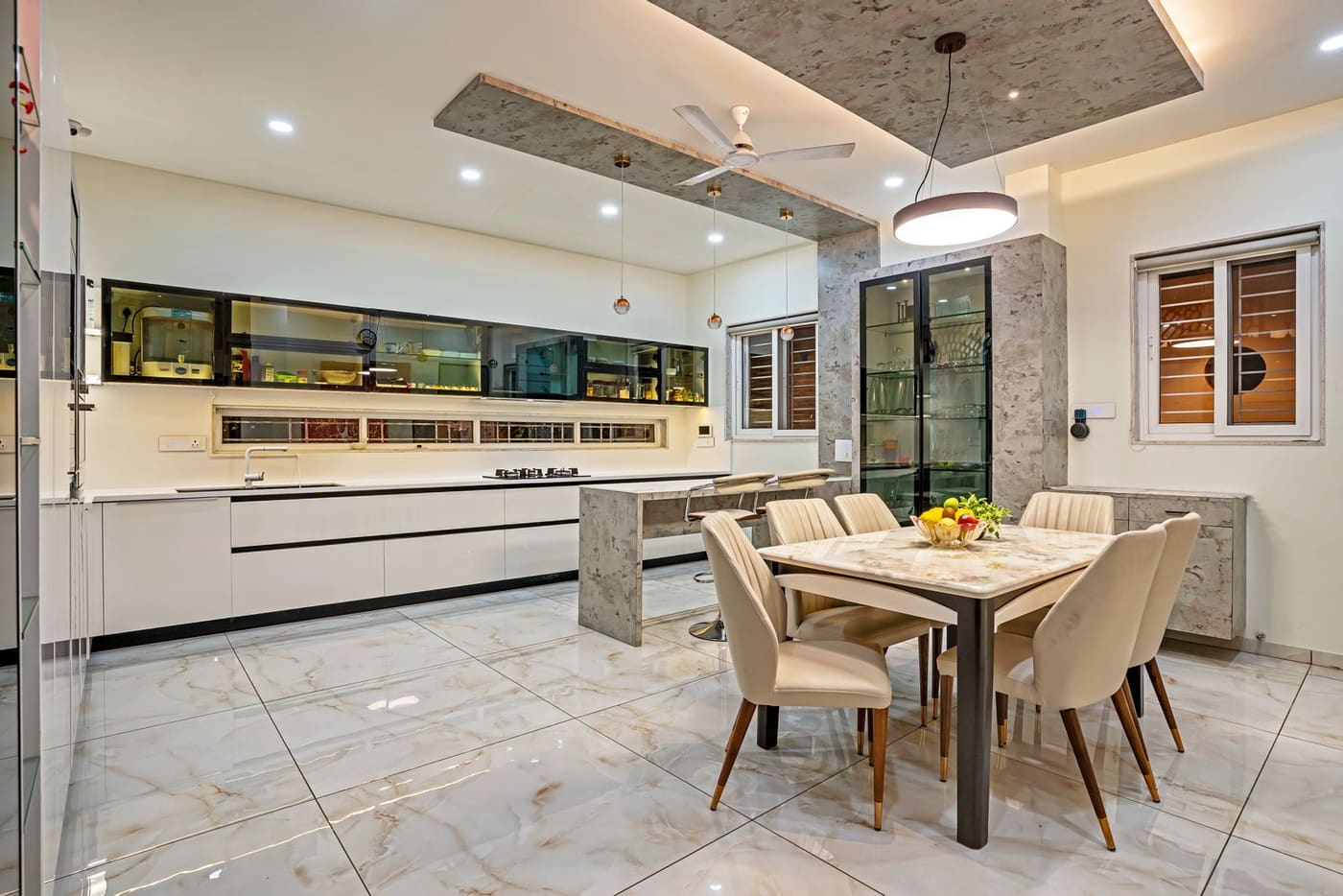 A finished kitchen and dining area with a false ceiling and marble floor